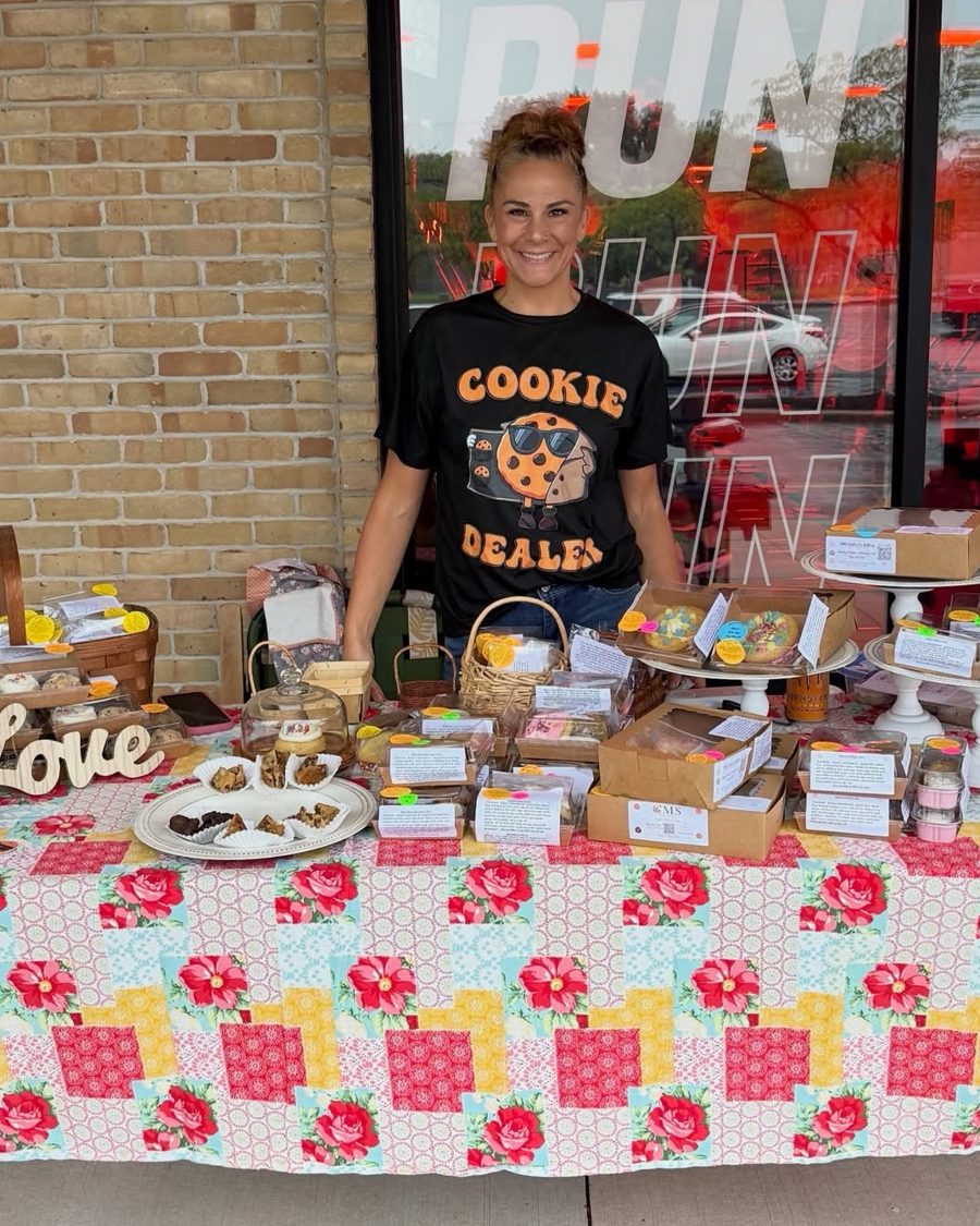 Shaun smiling behind her market table full of boxed cookies